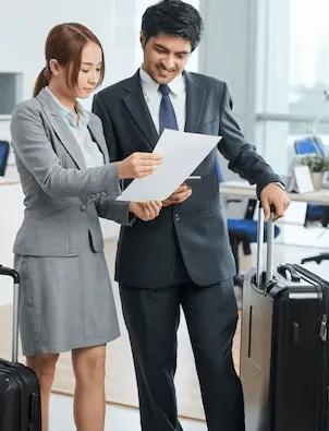 Mainland- Two professionals with a suitcase in an office, reviewing a document together.
