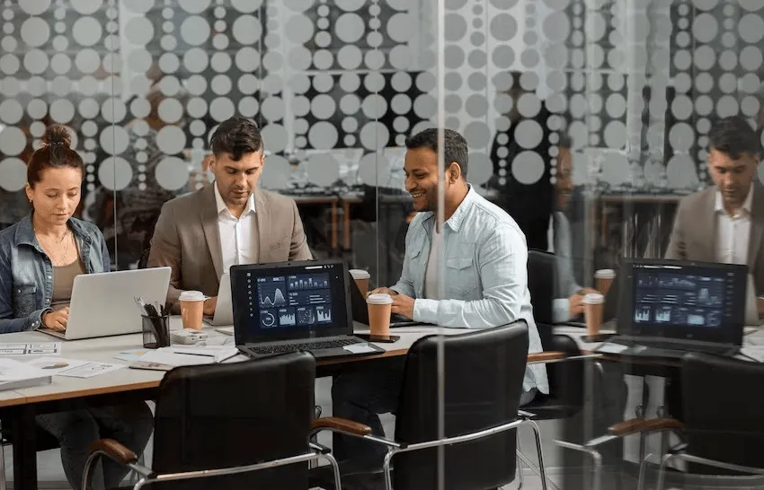  business setup services in uae -Group of professionals working on laptops in a modern office setting.