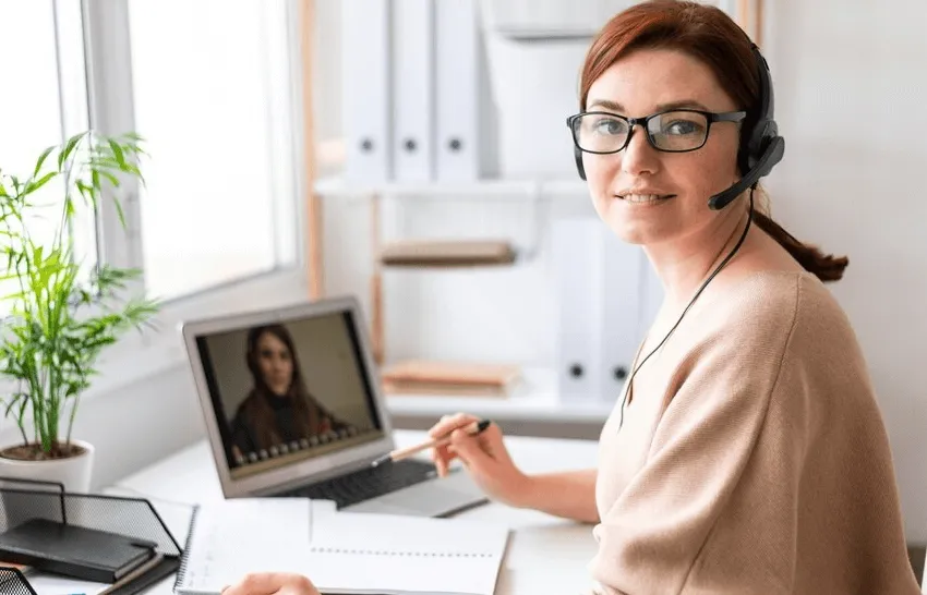 business setup services in uae -Person with headphones working on a laptop at a bright office desk.